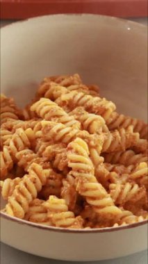 Kırmızı dolma biber sosuyla karıştırılmış makarna videosu.