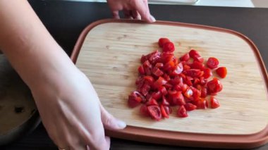 Bir kadın elinin tahta kesme tahtasıyla taze domatesleri doğradığı yakın çekim videosu.