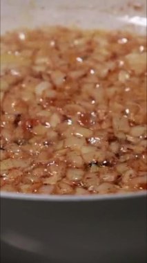 Tavada doğranmış soğanın pişirildiği dikey yakın çekim video.