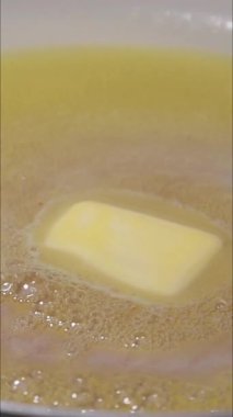 Tereyağının tavada yavaşça eridiği dikey yakın çekim videosu