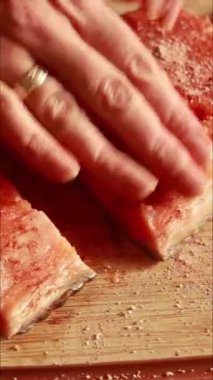 Tahta kesme tahtasında taze somon filetosu hazırlıyorum. Somon budanır, kurutulur, kurutulur ve terbiye edilir, pişirmeye hazırlanır.