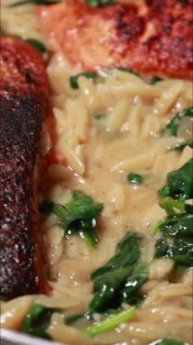 Lezzetli somon fileto tavada kızartılmış, kremalı orzo ve sotelenmiş ıspanakla servis ediliyor.