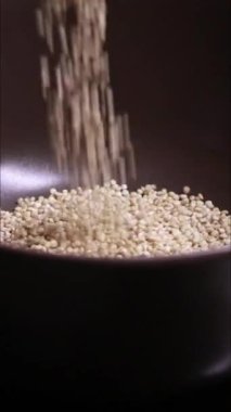 Sobanın üzerinde küçük bir tencerede kinoanın pişerken çekilmiş dikey yakın çekim videosu. Tahıllar suda yavaşça kaynayıp sağlıklı ve doğal gıda hazırlama sürecini sergiliyor.