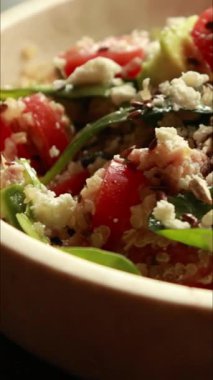  Protein ve sağlıklı yağlarla doldurulmuş kinoa salatası. İçinde avokado, nohut ve tohum gibi malzemeler var. Temiz, enerjik ve kasede servis edilen fitness dostu bir yemek.