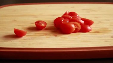 Tahta kesme tahtasının üzerinde taze domatesleri ikiye bölerken çekilmiş yakın çekim videosu.