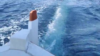 İnanılmaz açık mavi sularda yüzen bir teknenin arka görüntüsü