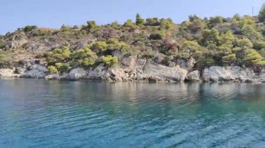 Makedonya bölgesindeki Chalkidiki yarımadasında, Selanik 'in güneydoğusunda Yunanistan' da yer alan Nikiti köyünün güzel kıyı şeridine yakın bir manzara. Sahne, sakin mavi suyu gösteren bir tekneden çekiliyor.
