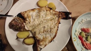 Izgara ibne balığı geleneksel Yunan restoranı tarzında servis edilir.