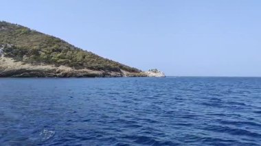 Makedonya bölgesindeki Chalkidiki yarımadasında, Selanik 'in güneydoğusunda Yunanistan' da yer alan Nikiti köyünün güzel kıyı şeridine yakın bir manzara. Sahne, sakin mavi suyu gösteren bir tekneden çekiliyor.