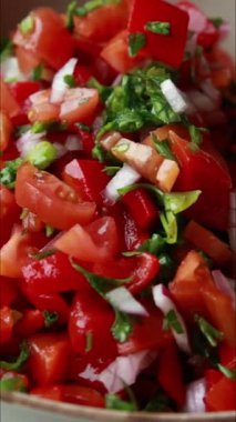  Fırında kırmızı biber, domates ve kırmızı soğan kullanarak bir kasede hazırlanan taze salsa 'nın yakın plan videosu.