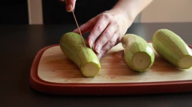 Kadının elleri, tahta bir kesme tahtasıyla taze kabağı ikiye bölüyor.