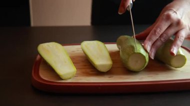 Kadının elleri, tahta bir kesme tahtasıyla taze kabağı ikiye bölüyor.