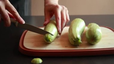 Kadının elleri, tahta bir kesme tahtasıyla taze kabağı ikiye bölüyor.