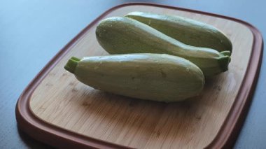 Kadının elleri, tahta bir kesme tahtasıyla taze kabağı ikiye bölüyor.