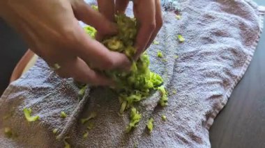 Taze kabak doğrayan ve fazla su çekmek için üzerine tuz serpiştiren bir kadının yakın plan fotoğrafı.