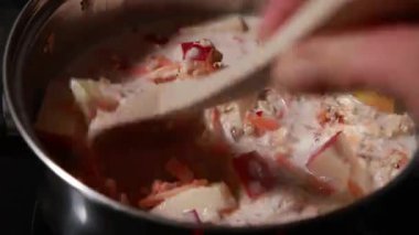 Sağlıklı ve lezzetli bir kahvaltı için elmalı ve havuçlu yulaf ezmesi hazırlamak ve pişirmek. Ev mutfağında sıcak bir yemek.