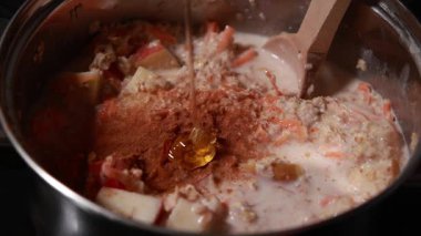 Sağlıklı ve lezzetli bir kahvaltı için elmalı ve havuçlu yulaf ezmesi hazırlamak ve pişirmek. Ev mutfağında sıcak bir yemek.