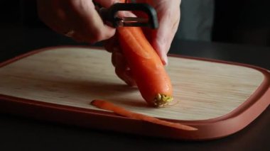  Kadınların elleri taze havucu soyarken tahta kesme tahtasına.