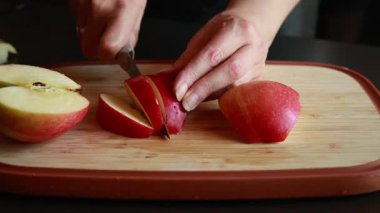 Kadınların elleri, taze bir elmayı tahta bir kesme tahtasıyla kesiyor.