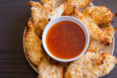  Hindistancevizi parçalarıyla kaplı tavuk filetoları, tatlı acı biber soslu bir tabağa konur. Tropikal lezzet yemeği, gevrek dokular, zengin bir tat. 