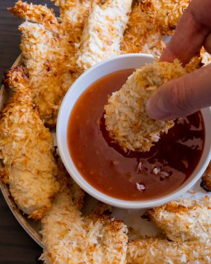  Hindistancevizi parçalarıyla kaplı tavuk filetoları, tatlı acı biber soslu bir tabağa konur. Tropikal lezzet yemeği, gevrek dokular, zengin bir tat. 