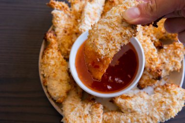  Hindistancevizi parçalarıyla kaplı tavuk filetoları, tatlı acı biber soslu bir tabağa konur. Tropikal lezzet yemeği, gevrek dokular, zengin bir tat. 