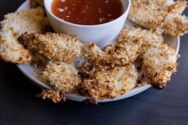  Hindistancevizi parçalarıyla kaplı tavuk filetoları, tatlı acı biber soslu bir tabağa konur. Tropikal lezzet yemeği, gevrek dokular, zengin bir tat. 