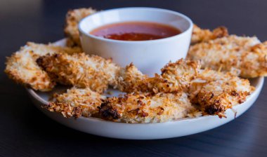  Hindistancevizi parçalarıyla kaplı tavuk filetoları, tatlı acı biber soslu bir tabağa konur. Tropikal lezzet yemeği, gevrek dokular, zengin bir tat. 