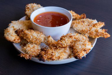  Hindistancevizi parçalarıyla kaplı tavuk filetoları, tatlı acı biber soslu bir tabağa konur. Tropikal lezzet yemeği, gevrek dokular, zengin bir tat. 