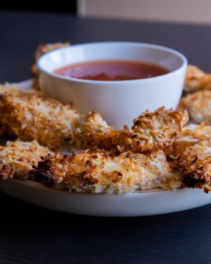  Hindistancevizi parçalarıyla kaplı tavuk filetoları, tatlı acı biber soslu bir tabağa konur. Tropikal lezzet yemeği, gevrek dokular, zengin bir tat. 