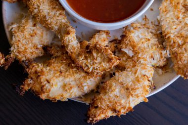  Hindistancevizi parçalarıyla kaplı tavuk filetoları, tatlı acı biber soslu bir tabağa konur. Tropikal lezzet yemeği, gevrek dokular, zengin bir tat. 