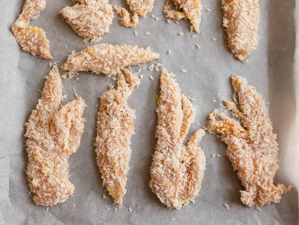 Hindistancevizi parçalarıyla kaplı çiğ tavuk filetolarının yakın plan fotoğrafı. Pişirmeye hazır. Taze, sağlıklı ve lezzetli tropikal yemek hazırlığı..