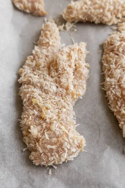 Hindistancevizi parçalarıyla kaplı çiğ tavuk filetolarının yakın plan fotoğrafı. Pişirmeye hazır. Taze, sağlıklı ve lezzetli tropikal yemek hazırlığı..