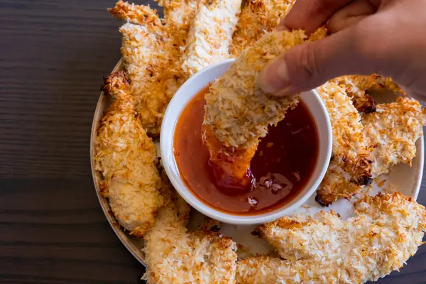  Hindistancevizi parçalarıyla kaplı tavuk filetoları, tatlı acı biber soslu bir tabağa konur. Tropikal lezzet yemeği, gevrek dokular, zengin bir tat. 