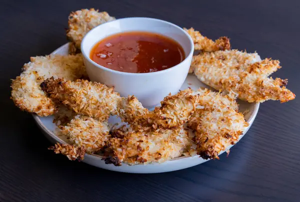  Hindistancevizi parçalarıyla kaplı tavuk filetoları, tatlı acı biber soslu bir tabağa konur. Tropikal lezzet yemeği, gevrek dokular, zengin bir tat. 