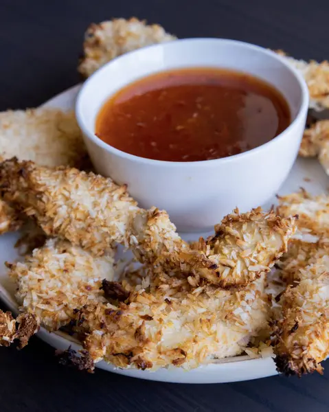  Hindistancevizi parçalarıyla kaplı tavuk filetoları, tatlı acı biber soslu bir tabağa konur. Tropikal lezzet yemeği, gevrek dokular, zengin bir tat. 