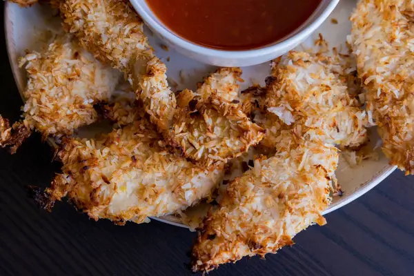  Hindistancevizi parçalarıyla kaplı tavuk filetoları, tatlı acı biber soslu bir tabağa konur. Tropikal lezzet yemeği, gevrek dokular, zengin bir tat. 