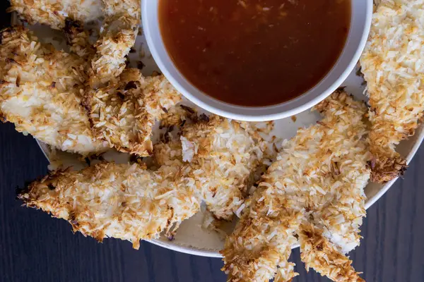  Hindistancevizi parçalarıyla kaplı tavuk filetoları, tatlı acı biber soslu bir tabağa konur. Tropikal lezzet yemeği, gevrek dokular, zengin bir tat. 