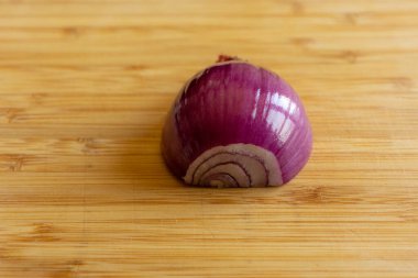 Ahşap bir tahtanın üzerinde duran yarım mor soğanın yakın plan fotoğrafı..