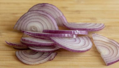 Tahtadaki kırmızı soğan dilimlerinin yakın plan fotoğrafı.