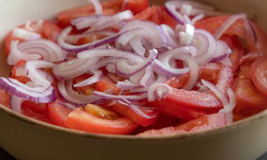 Taze doğranmış domateslerin ve kırmızı soğanın yakın plan fotoğrafı. Parlak kırmızı domates ve mor soğan halkaları.