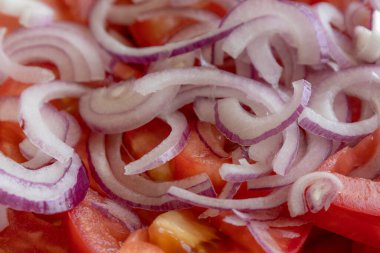 Taze doğranmış domateslerin ve kırmızı soğanın yakın plan fotoğrafı. Parlak kırmızı domates ve mor soğan halkaları.