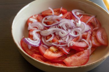 Taze doğranmış domateslerin ve kırmızı soğanın yakın plan fotoğrafı. Parlak kırmızı domates ve mor soğan halkaları.