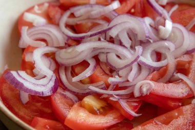 Taze doğranmış domateslerin ve kırmızı soğanın yakın plan fotoğrafı. Parlak kırmızı domates ve mor soğan halkaları.
