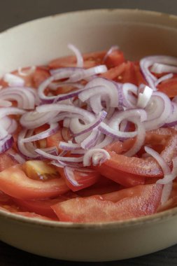 Taze doğranmış domateslerin ve kırmızı soğanın yakın plan fotoğrafı. Parlak kırmızı domates ve mor soğan halkaları.