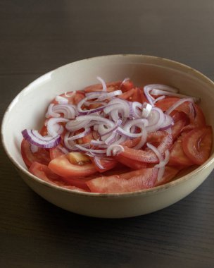 Taze doğranmış domateslerin ve kırmızı soğanın yakın plan fotoğrafı. Parlak kırmızı domates ve mor soğan halkaları.
