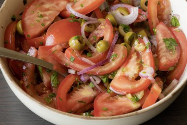 Kâsede taze ve basit bir domates salatası. Bitkilerle sulu kırmızı domateslerin yakın plan görüntüsü. Hafif ve sağlıklı mevsimlik yemekler için mükemmel..