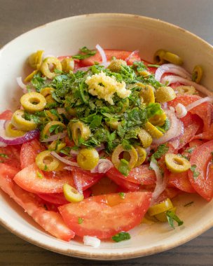 Kâsede taze ve basit bir domates salatası. Bitkilerle sulu kırmızı domateslerin yakın plan görüntüsü. Hafif ve sağlıklı mevsimlik yemekler için mükemmel..