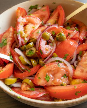 Kâsede taze ve basit bir domates salatası. Bitkilerle sulu kırmızı domateslerin yakın plan görüntüsü. Hafif ve sağlıklı mevsimlik yemekler için mükemmel..