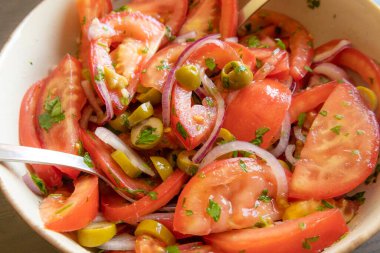 Kâsede taze ve basit bir domates salatası. Bitkilerle sulu kırmızı domateslerin yakın plan görüntüsü. Hafif ve sağlıklı mevsimlik yemekler için mükemmel..